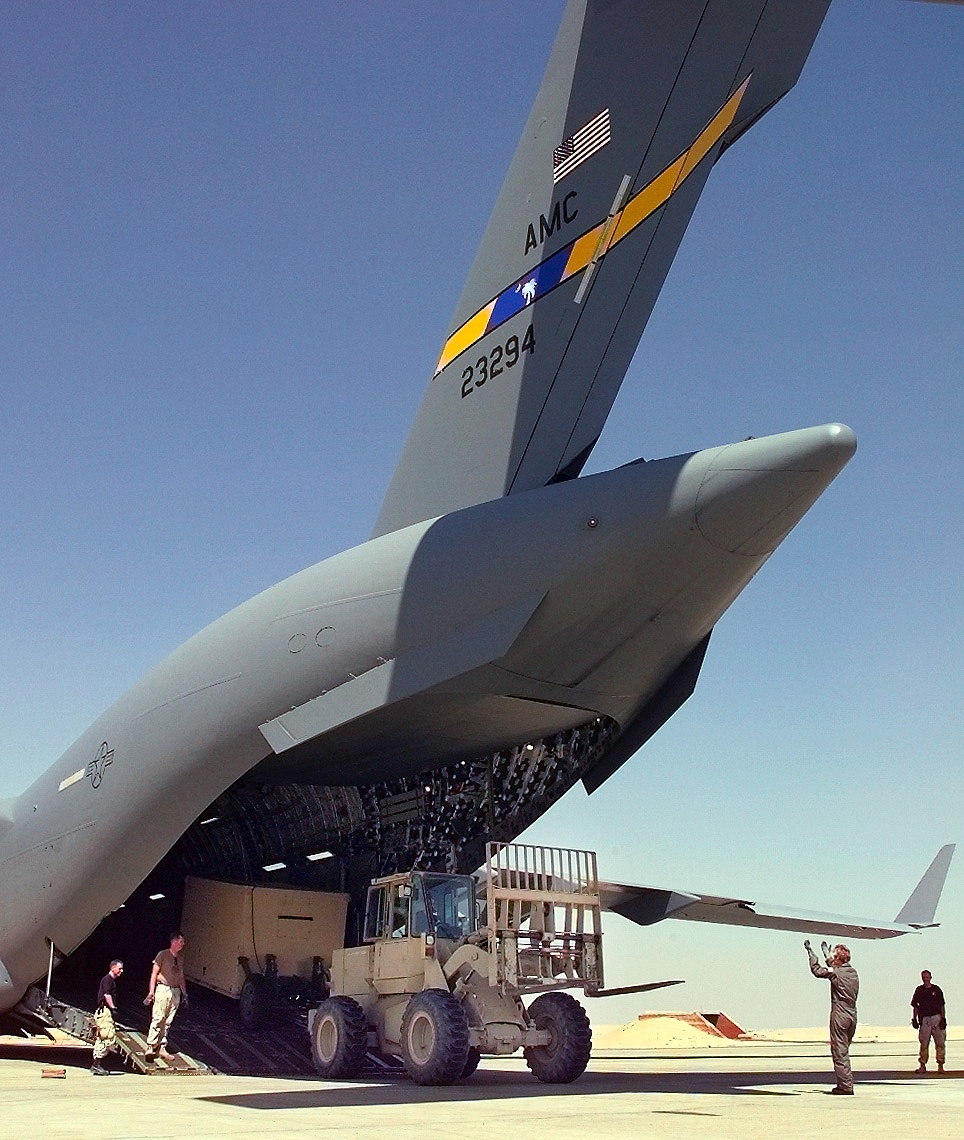 A crew member of a C-17 Globemaster III directs a fork lift operator as equipment and personnel are unloaded at Cairo West.