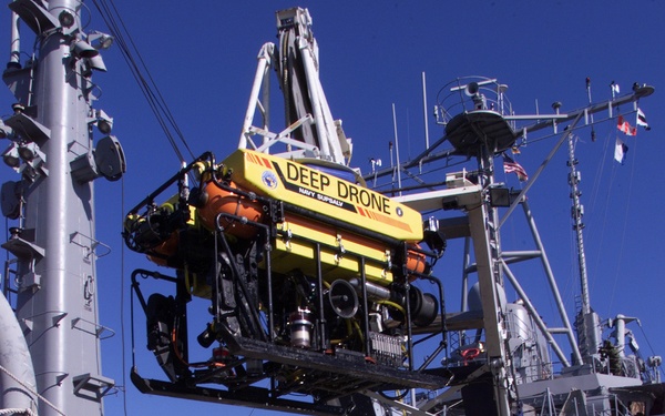 Crew members of the USS Grapple lower the Deep Diving Submersible Drone into the water at Naval Station Newport, R.I.