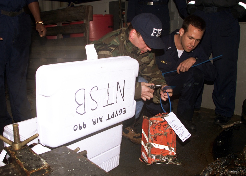 Lt. j.g. Hall watches as FBI Agent Duback tags the cockpit voice recorder from EgyptAir Flight 990 on the USS Grapple.