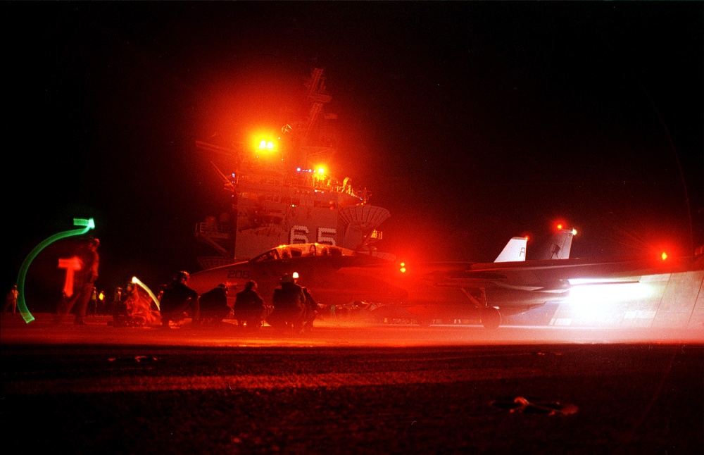 A U.S. Navy F-14A Tomcat goes into full afterburner as it prepares to catapult from the flight deck of USS Enterprise.