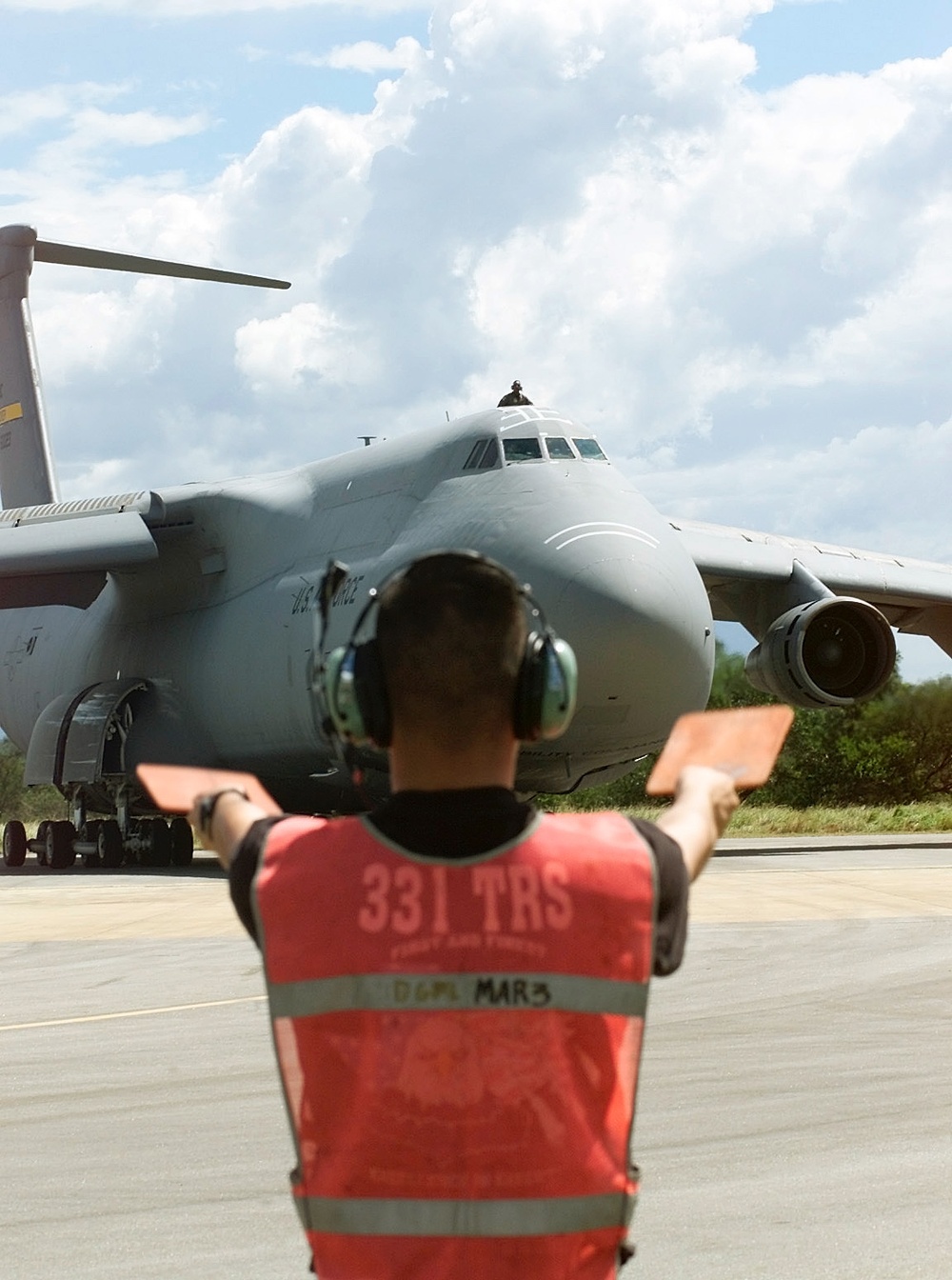 Airman 1st Class Andre Raymundo directs a C-5 Galaxy to a parking spot at Hoedspruit Air Force Base, South Africa.