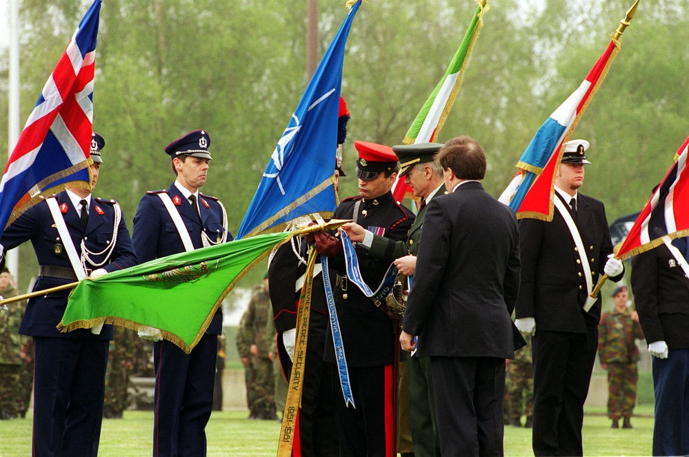 Gen. Wesley K. Clark attaches the Joint Meritorious Unit Award to the unit colors in Mons, Belgium.