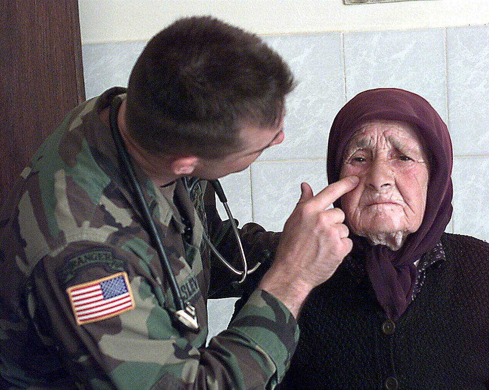 1st Lt. John Slevin, a U.S. Army physician's assistant, checks the face of an elderly Serbian woman.