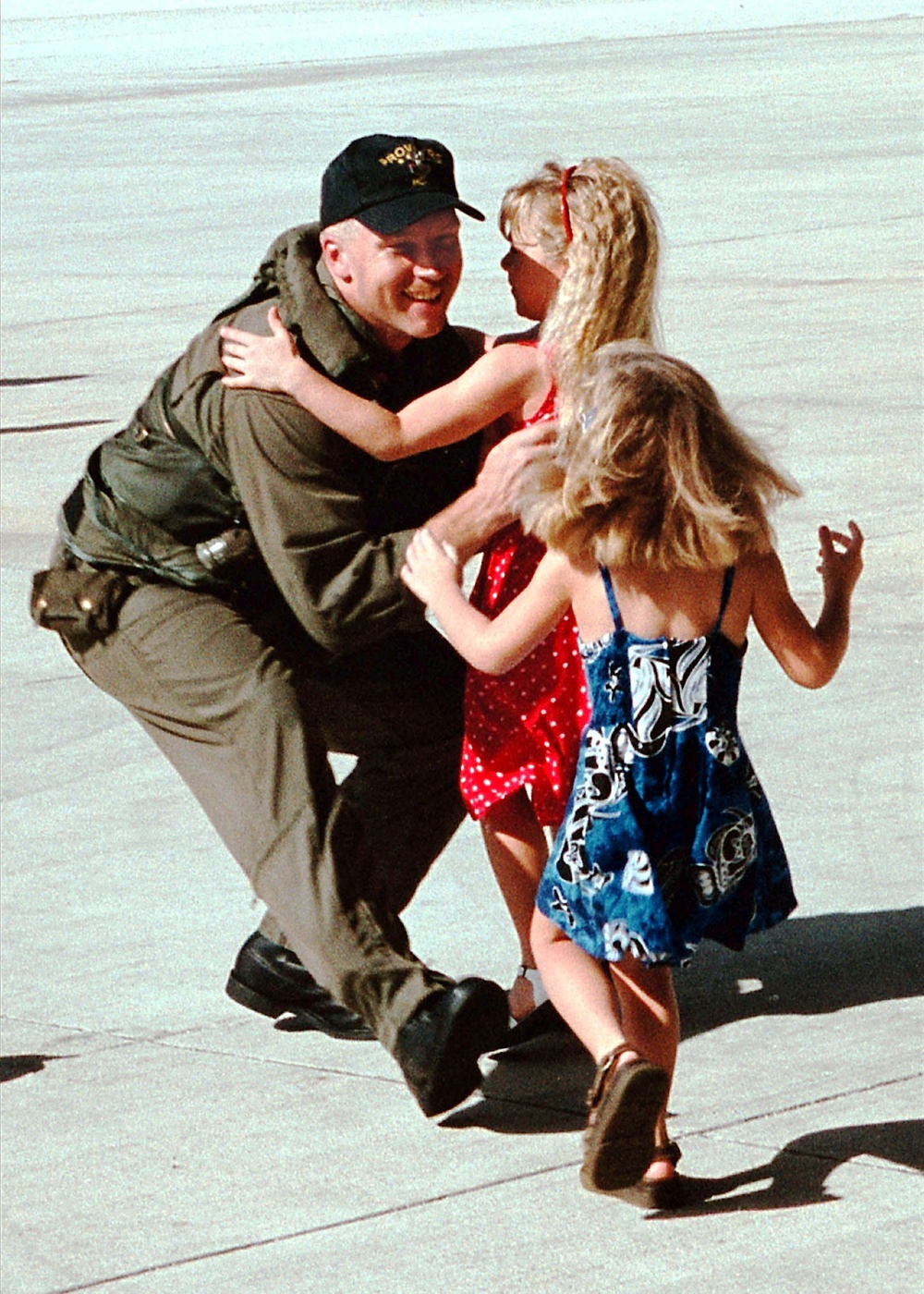 Petty Officer 1st Class Sam Wood rushes to embrace his daughters as he returns to Yigo, Guam.