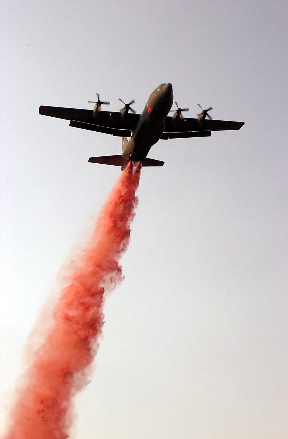 A C-130 Hercules equipped with the Modular Airborne Fire Fighting System streams a charge of Phos-Chek fire retardant.