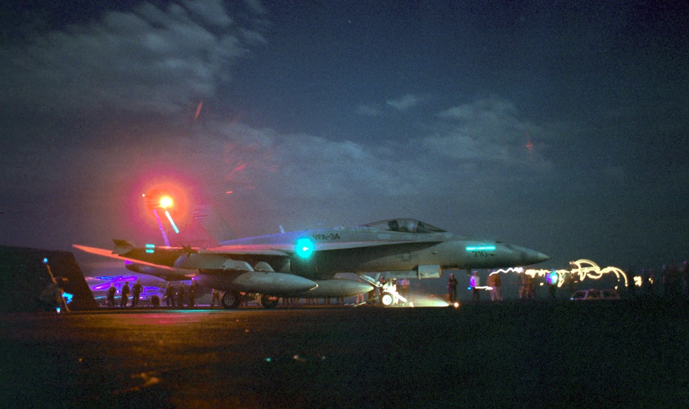 An F/A-18C Hornet is prepared for a night catapult launch from the aircraft carrier USS George Washington in the Persian Gulf.