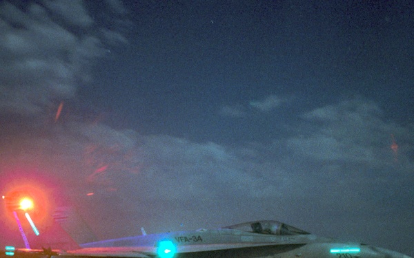 An F/A-18C Hornet is prepared for a night catapult launch from the aircraft carrier USS George Washington in the Persian Gulf.