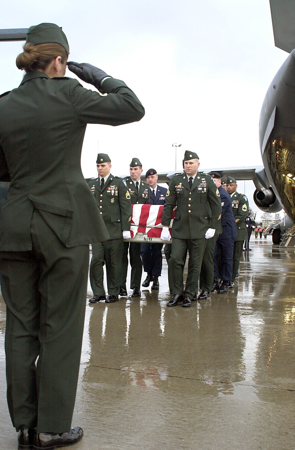 A soldier salutes a fallen comrade as casket bearers carry the remains of one of six U.S. servicemen killed in a training exercise in Kuwait.