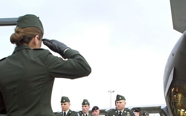 A soldier salutes a fallen comrade as casket bearers carry the remains of one of six U.S. servicemen killed in a training exercise in Kuwait.