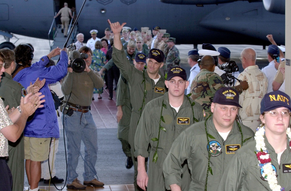 Navy Petty Officer Josef Edmunds waves to the crowd welcoming him and his fellow crew members to Hickam Air Force Base.