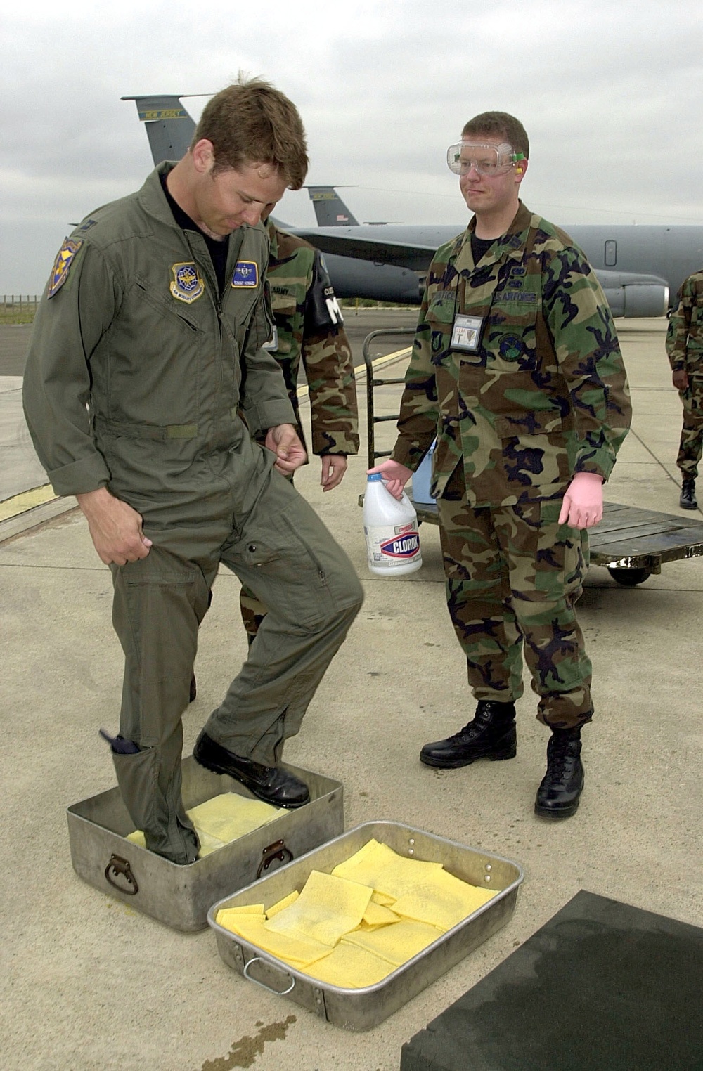 Air Force Capt. Tommy Howard steps into pans of bleach on the tarmac at Istres, France, to disinfect his shoes.