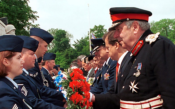 Senior Airman Rebecca A. Baucum passes a wreath to Lord Lieutenant of Cambridgeshire James Crowden.