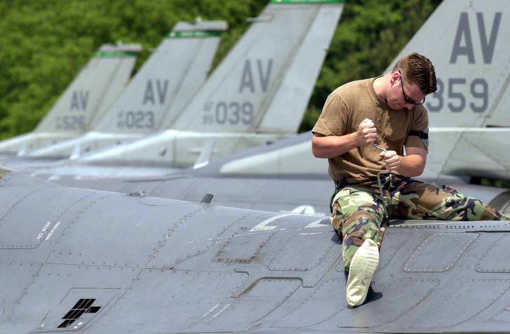 Airman 1st Class John McKivitz performs an operational check on the air refueling door of an F-16 Fighting Falcon.