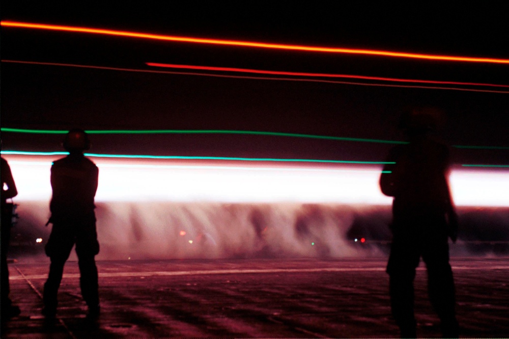 The night launch of a Navy F-14 Tomcat becomes a trail of steam and light on the USS Enterprise.