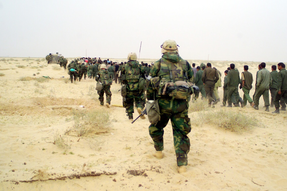 U.S. Marines escort captured enemy prisoners of war to a holding area in the desert of Iraq.