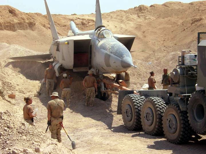 U.S. forces use heavy equipment to pull a MiG-25R Foxbat-B from beneath the sands in Iraq.