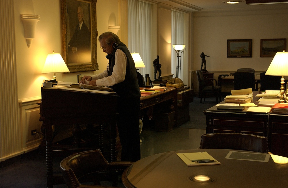 Secretary Rumsfeld works at his desk and talks on the phone while in his office at the Pentagon.
