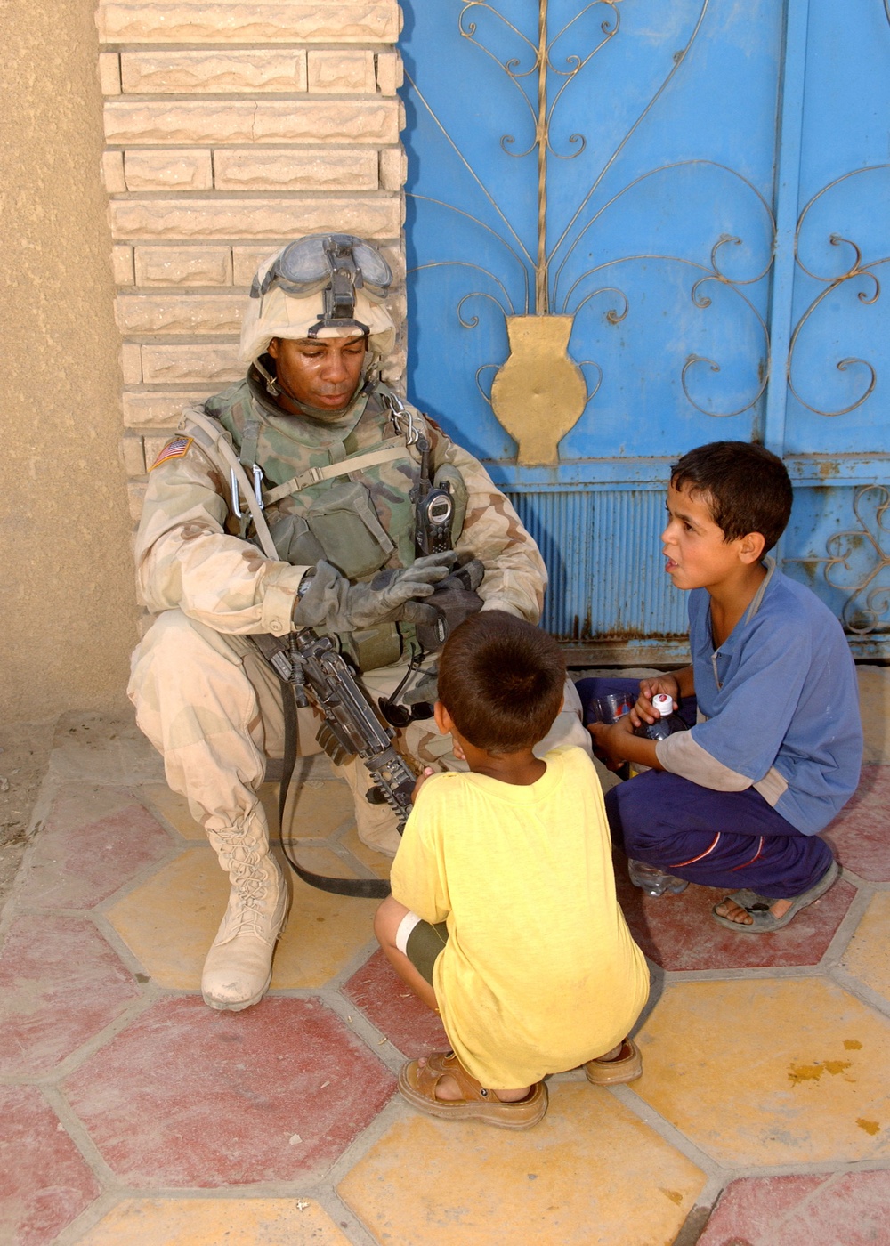 A U.S. Army soldier spends some spare time talking with two local boys in Sadr City, Iraq.