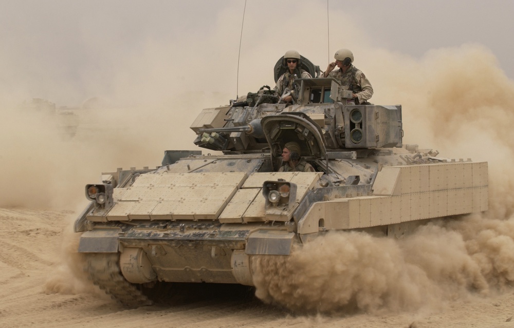 An M2A2 Bradley Fighting Vehicle kicks up plumes of dust.