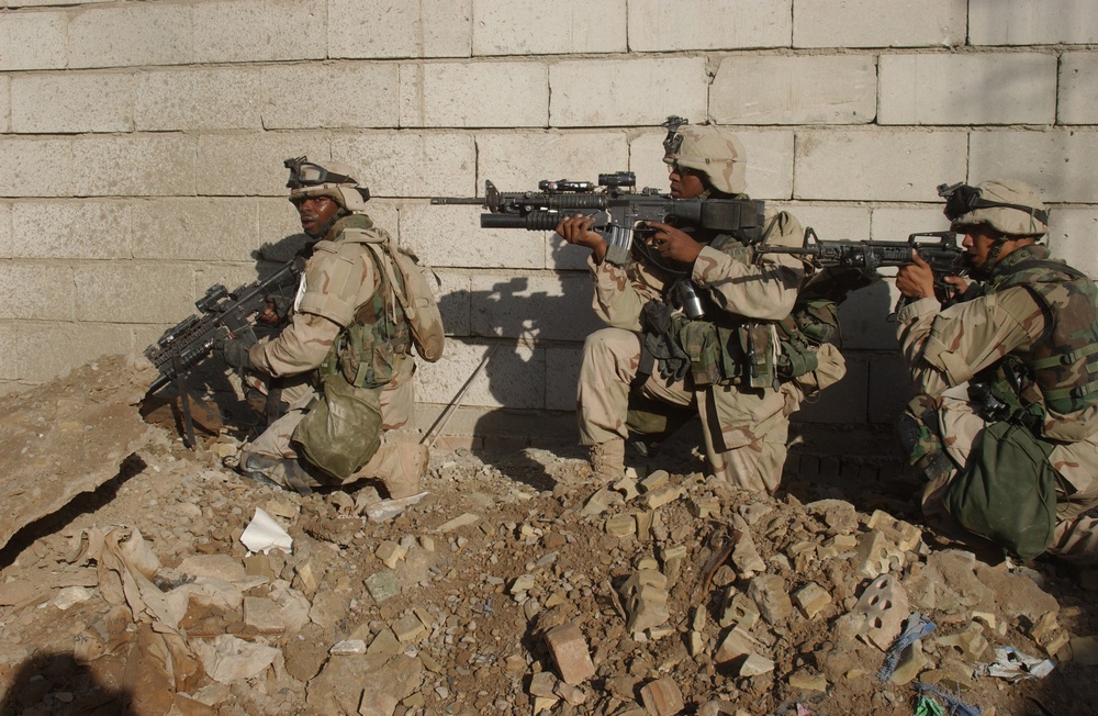 U.S. Army soldiers move along a wall as they clear buildings in Fallujah, Iraq