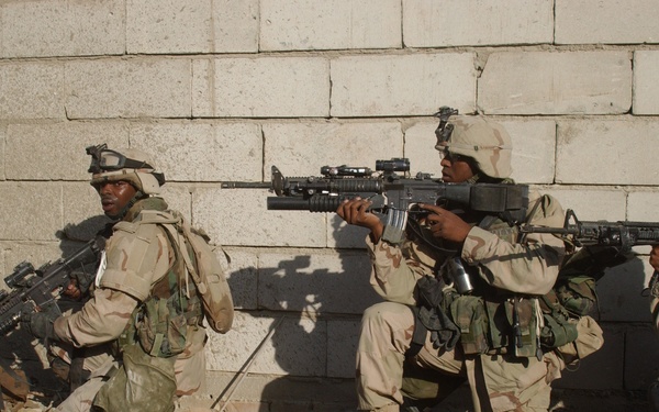 U.S. Army soldiers move along a wall as they clear buildings in Fallujah, Iraq