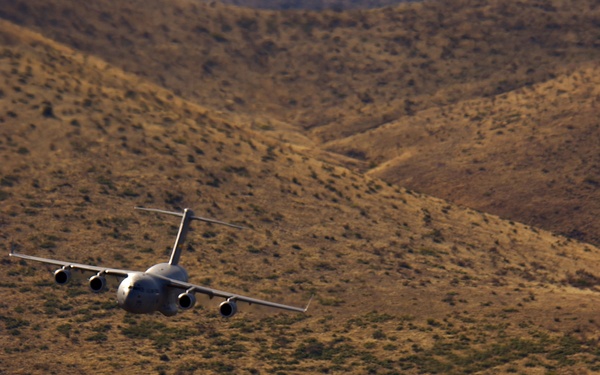 Two U.S. Air Force C-17 Globemasters III fly at low levels.