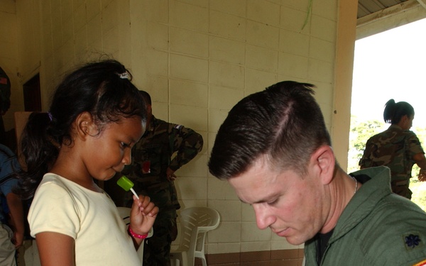 Air Force Lt. Col. Theodore Corallo helps a Honduran girl open her gift.