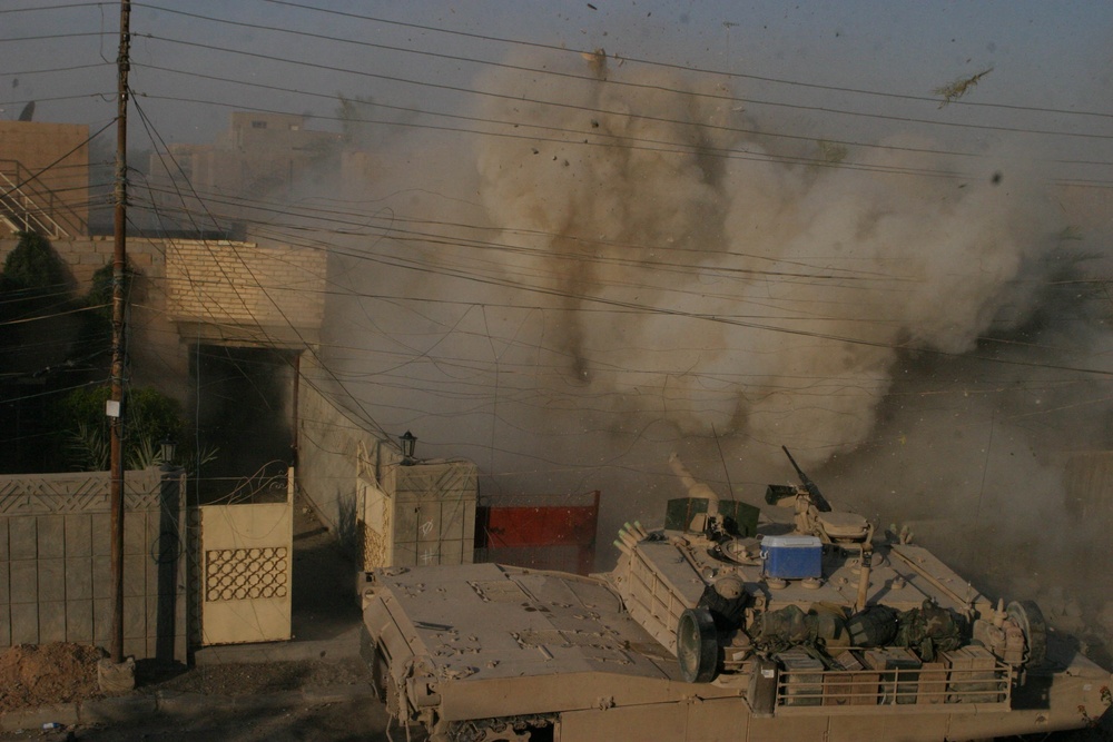 A U.S. Marine Corps M1A1 Abrams tank fires into a building.