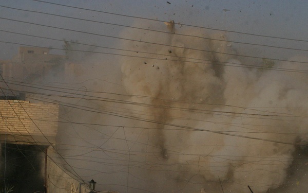 A U.S. Marine Corps M1A1 Abrams tank fires into a building.