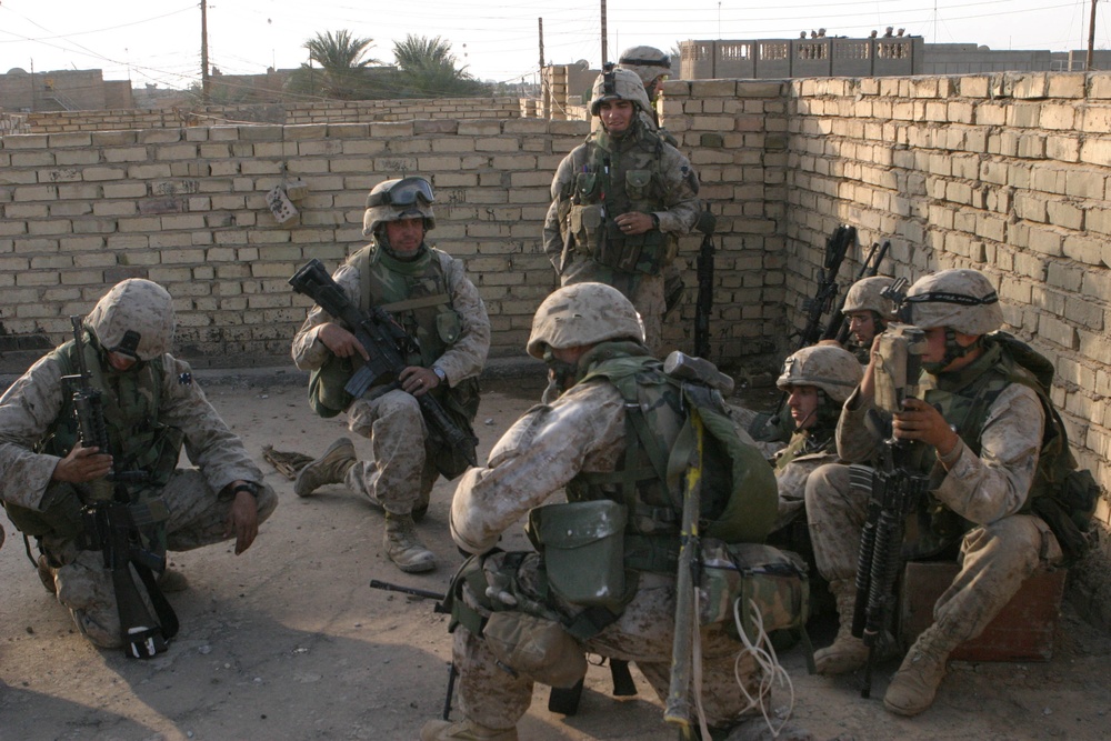 U.S. Marines huddle behind walls as they receive instructions.