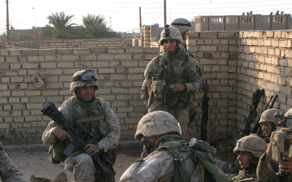 U.S. Marines huddle behind walls as they receive instructions.