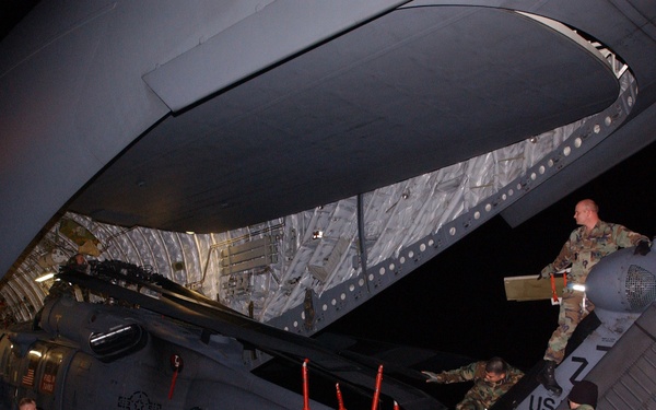 Air Force airmen carefully guide an HH-60 Pavehawk helicopter into a C-17 Globemaster III.