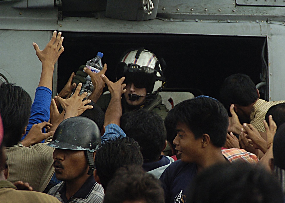 Indonesians swarm around a U.S. Navy helicopter.