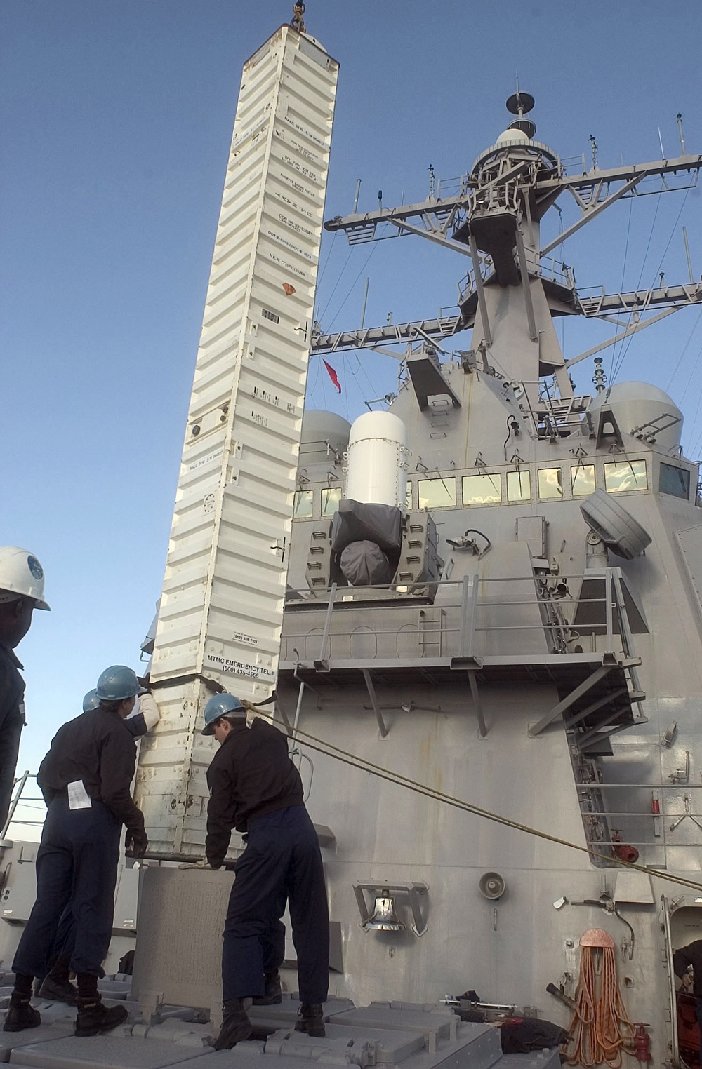 Sailors aboard the guided missile destroyer USS Curtis Wilbur (DDG 54) stabilize a shipping container.