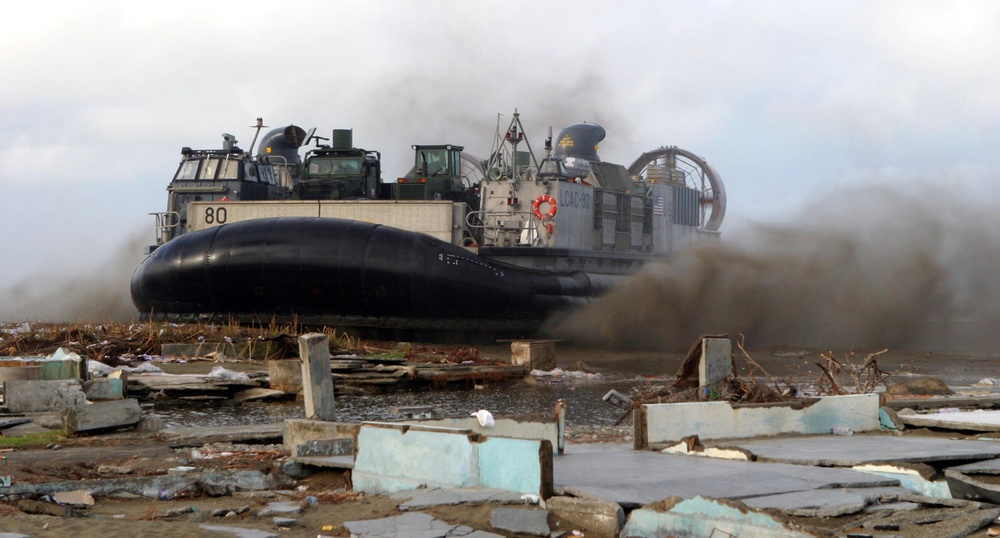 A U.S. Navy Landing Craft Air Cushion blows up sand as it lands on the beach.