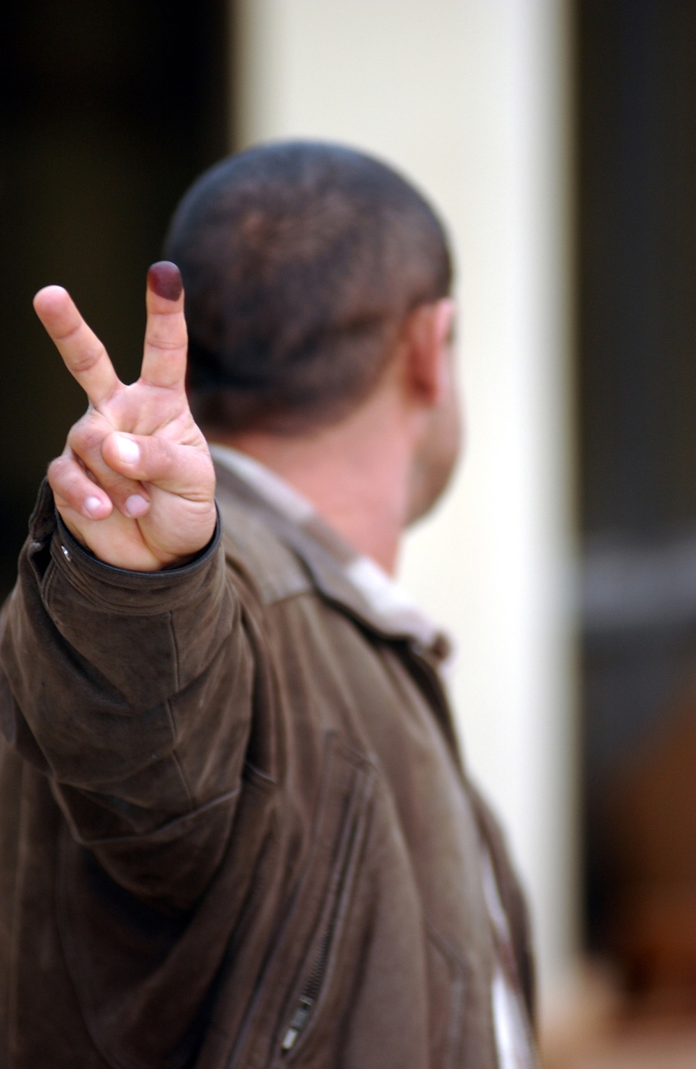 An Iraqi citizen, turning his head to protect his identity, proudly displays the indelible ink on his finger.