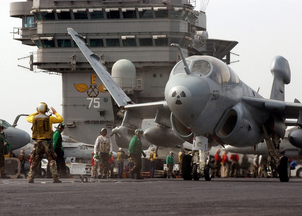 An EA-6B Prowler unfolds its wings as it is directed to a catapult for launch.