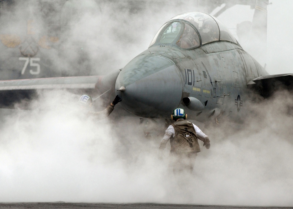 Steam from the catapult envelopes a Navy F-14 Tomcat.
