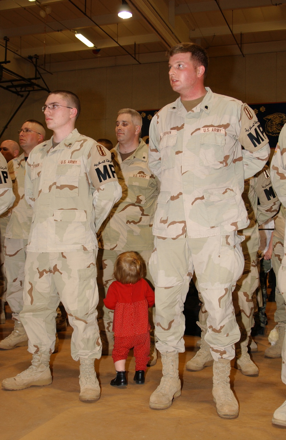 A little girl looks for her father in a military formation during a homecoming ceremony.