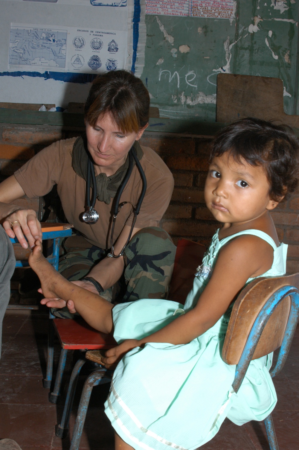 Petty Officer 1st Class Margaret Simpson checks a young girl's foot for skin infection.