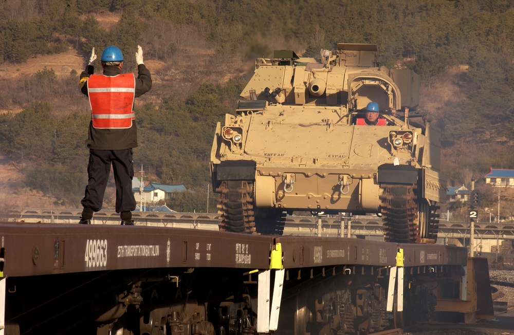 A Korean contractor directs the driver of an U.S. Army M577 Command Post Carrier.