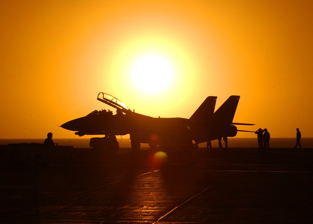 The setting sun silhouettes an F-14D Tomcat after a day of flight operations.