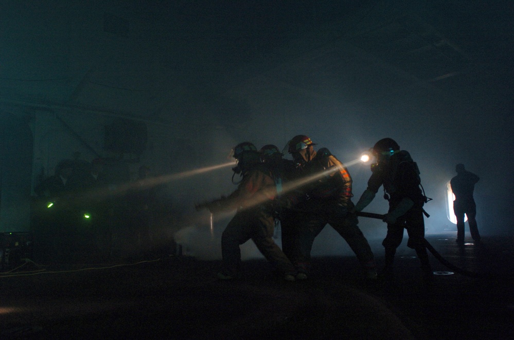 A fire fighting team works in the darkness to put out a simulated fire.