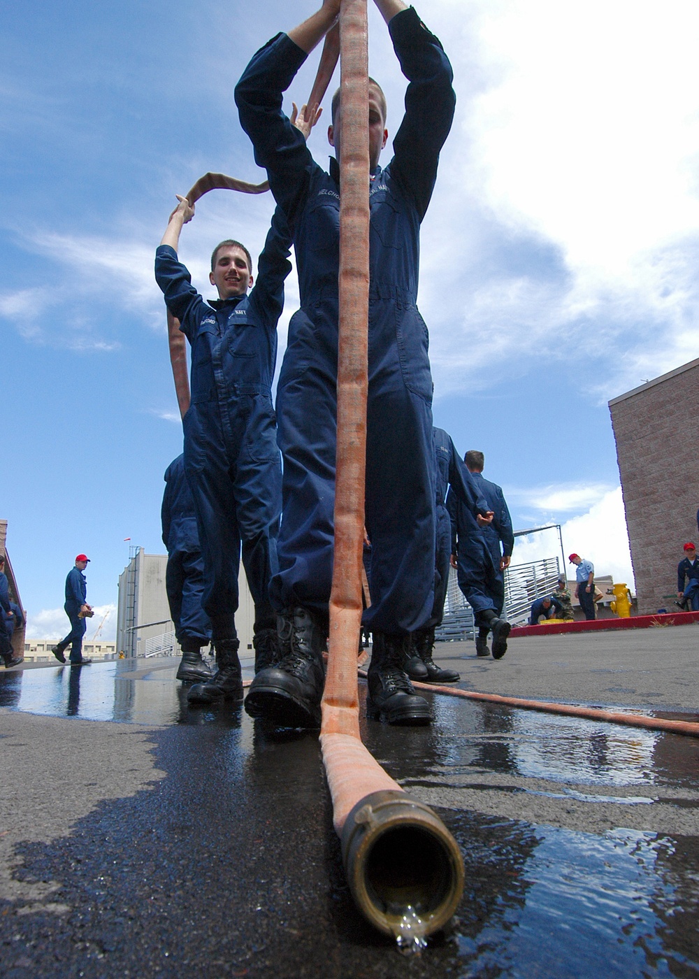 Sailors of the guided missile frigate USS Crommelin (FFG 37) drain a hose.