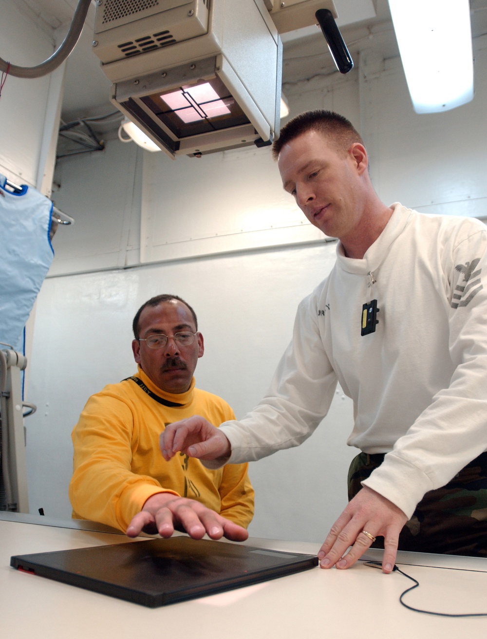 Navy Petty Officer 1st Class Troy Murphy prepares a patient's hand for an X-ray. Navy Petty Officer 1st Class Troy Murphy prepares a patient's hand for an X-ray.