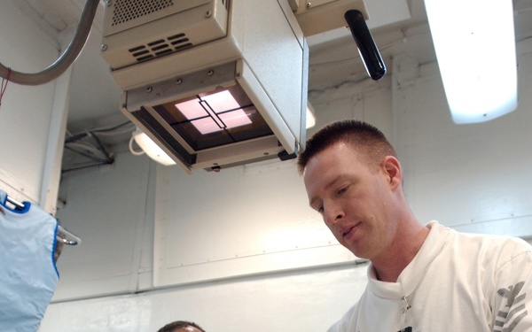 Navy Petty Officer 1st Class Troy Murphy prepares a patient's hand for an X-ray.