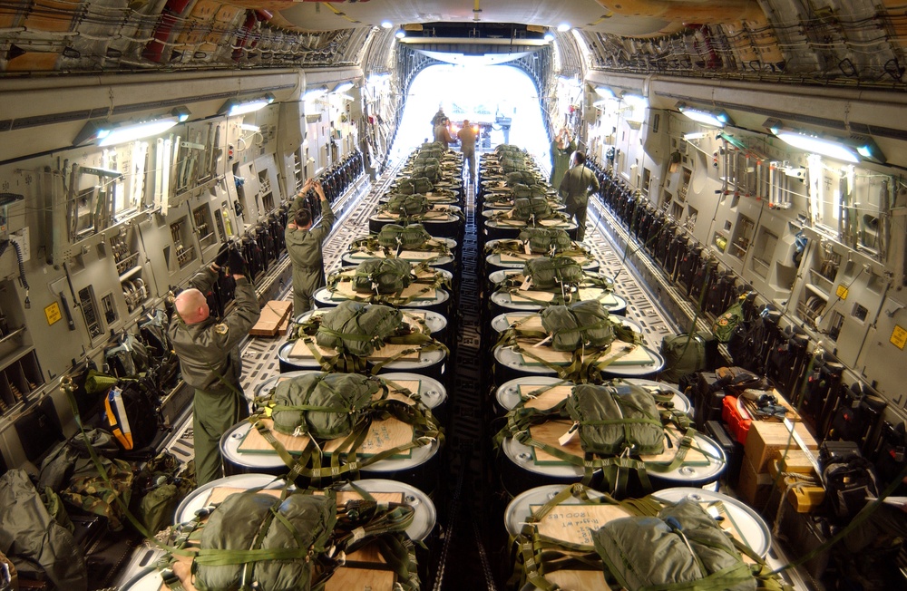 The crew of an Air Force C-17 Globemaster III loads pallets of 55-gallon drums.