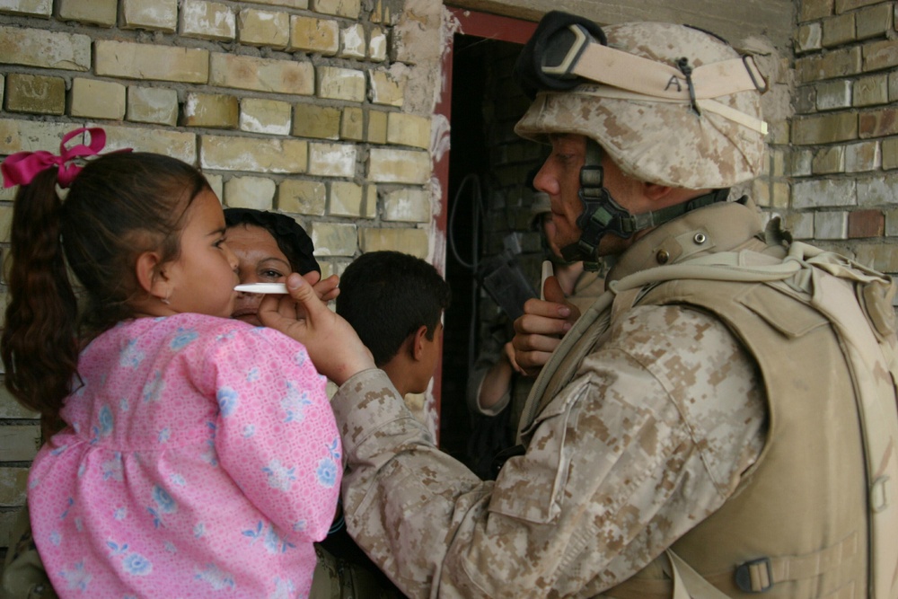 Navy Hospitalman Kevin Crim uses a thermometer to check the temperature of a sick Iraqi child.