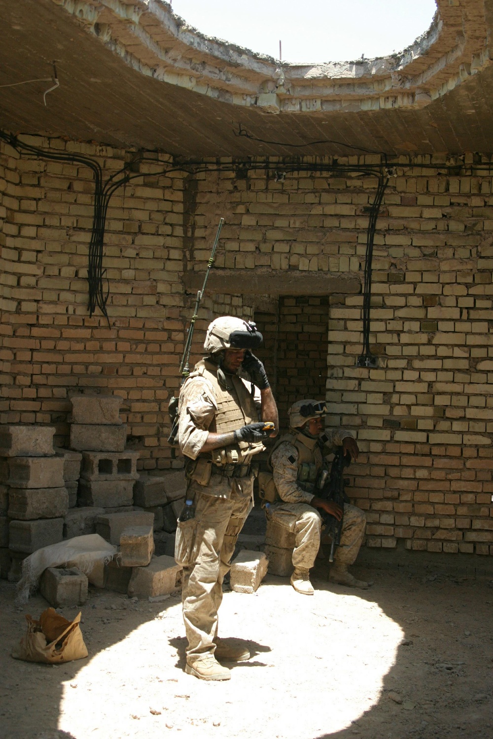 Marine Lance Cpl. Jamie Davidson is bathed in light from a hole in the roof as he radios in his current position.