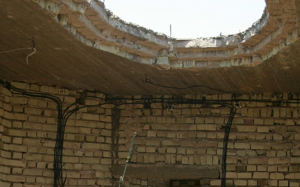 Marine Lance Cpl. Jamie Davidson is bathed in light from a hole in the roof as he radios in his current position.